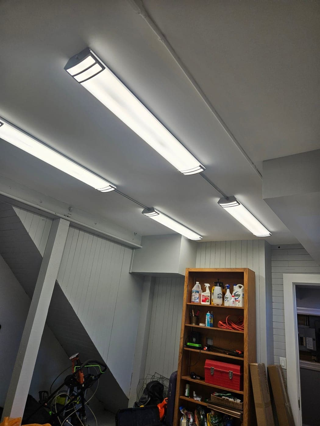 A row of linear LED shop lights running the length of a finished garage ceiling